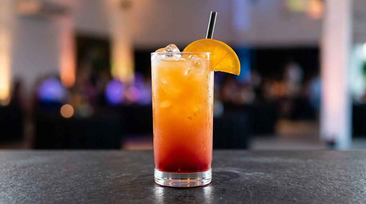 Sex on the Beach com gelo, degradê laranja e vermelho e laranja apoiada na borda.